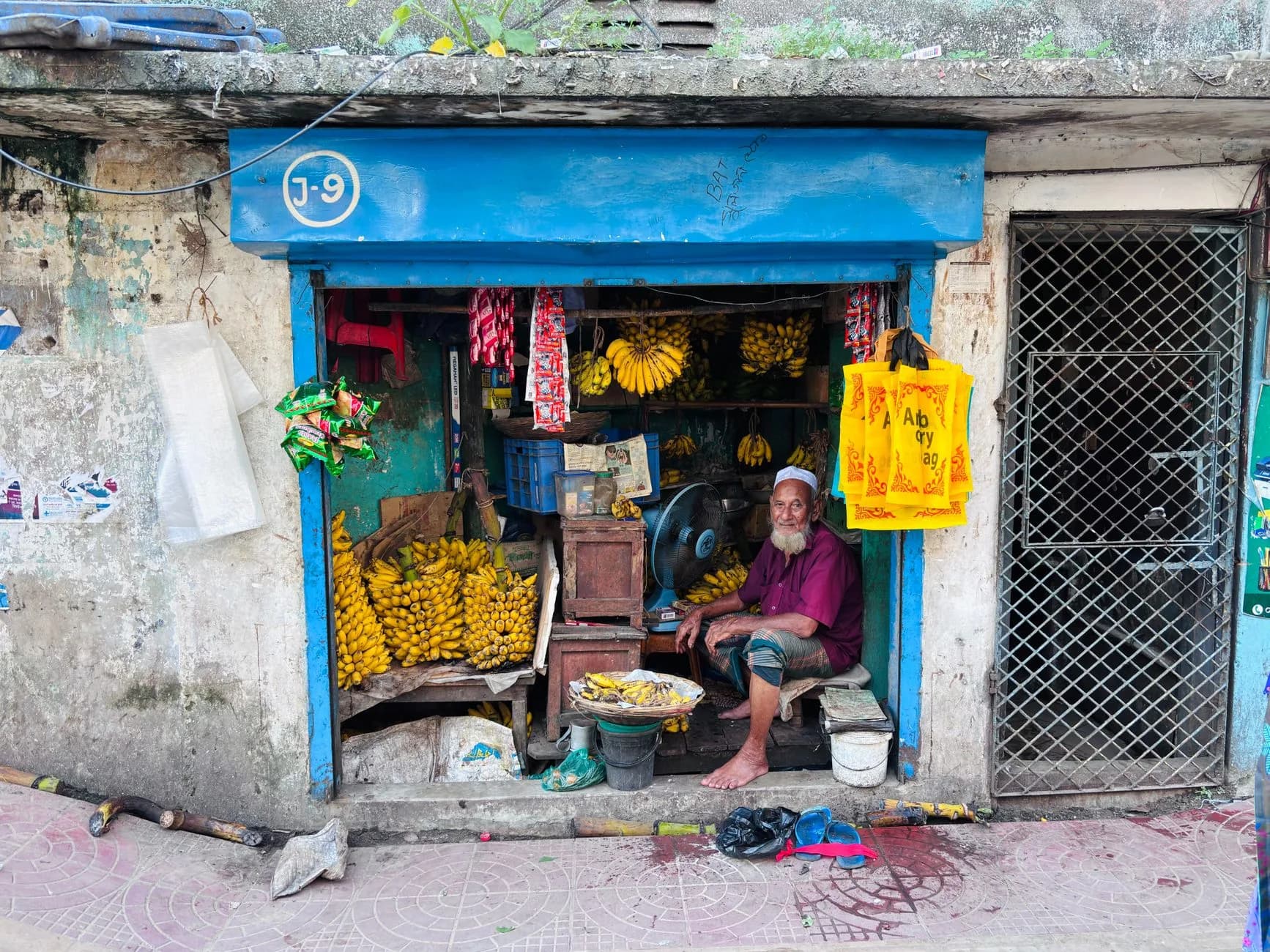 Street vendor selling bananas in a vibrant market stall with traditional elements.