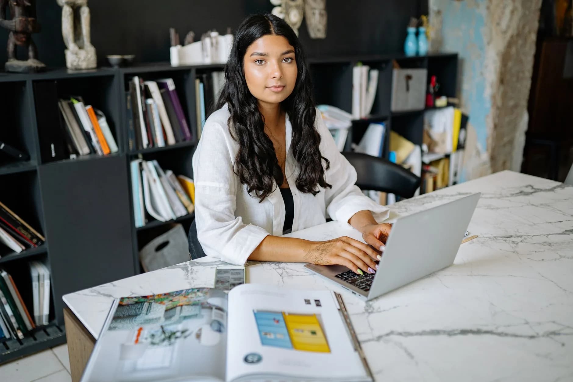 Professional woman focused on work in modern office with marble table and background decoration.