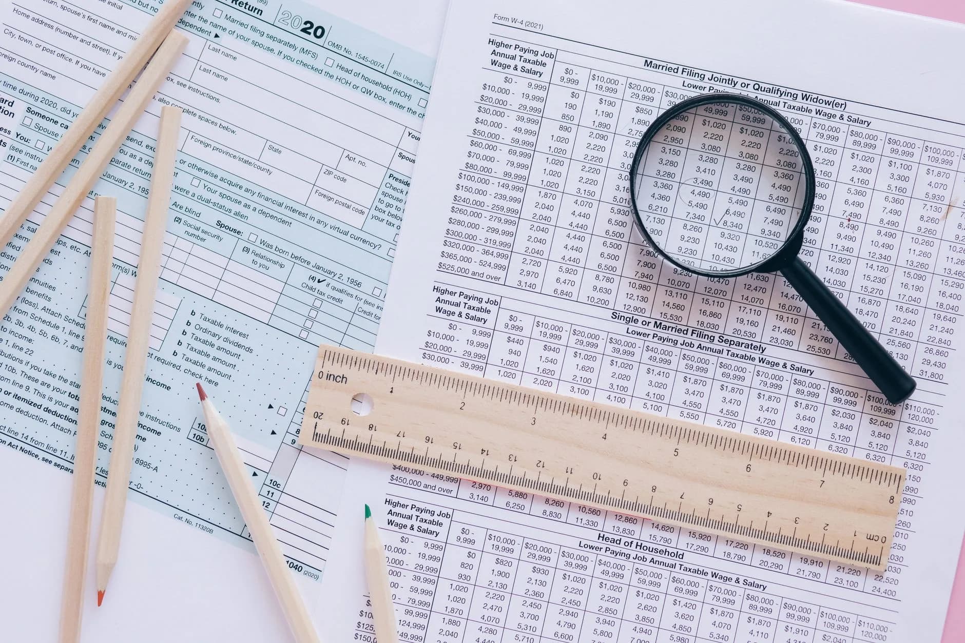 A high angle view showing IRS tax forms with pencils, ruler, and magnifying glass for financial planning.