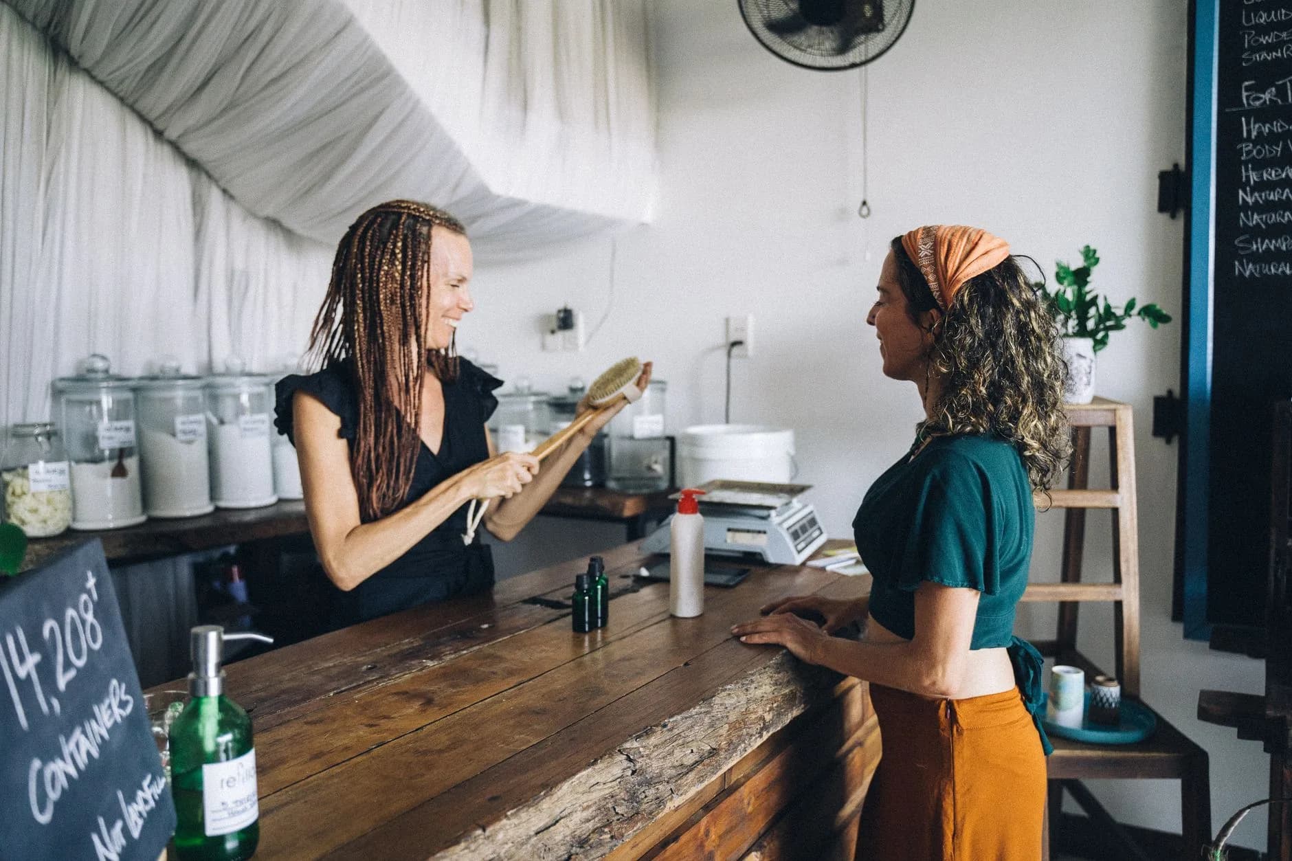 Two women in an eco-friendly store with refillable containers and glass jars.
