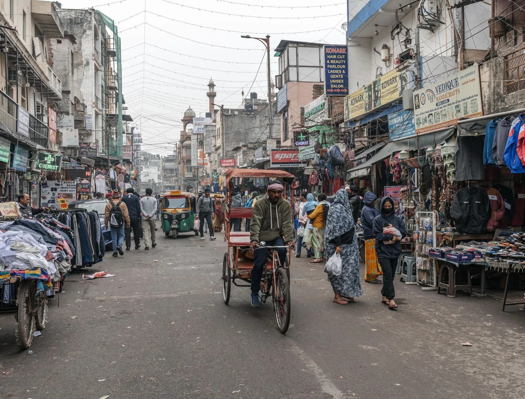 Vibrant street scene in New Delhi with people, shops, and a rickshaw in a busy marketplace.