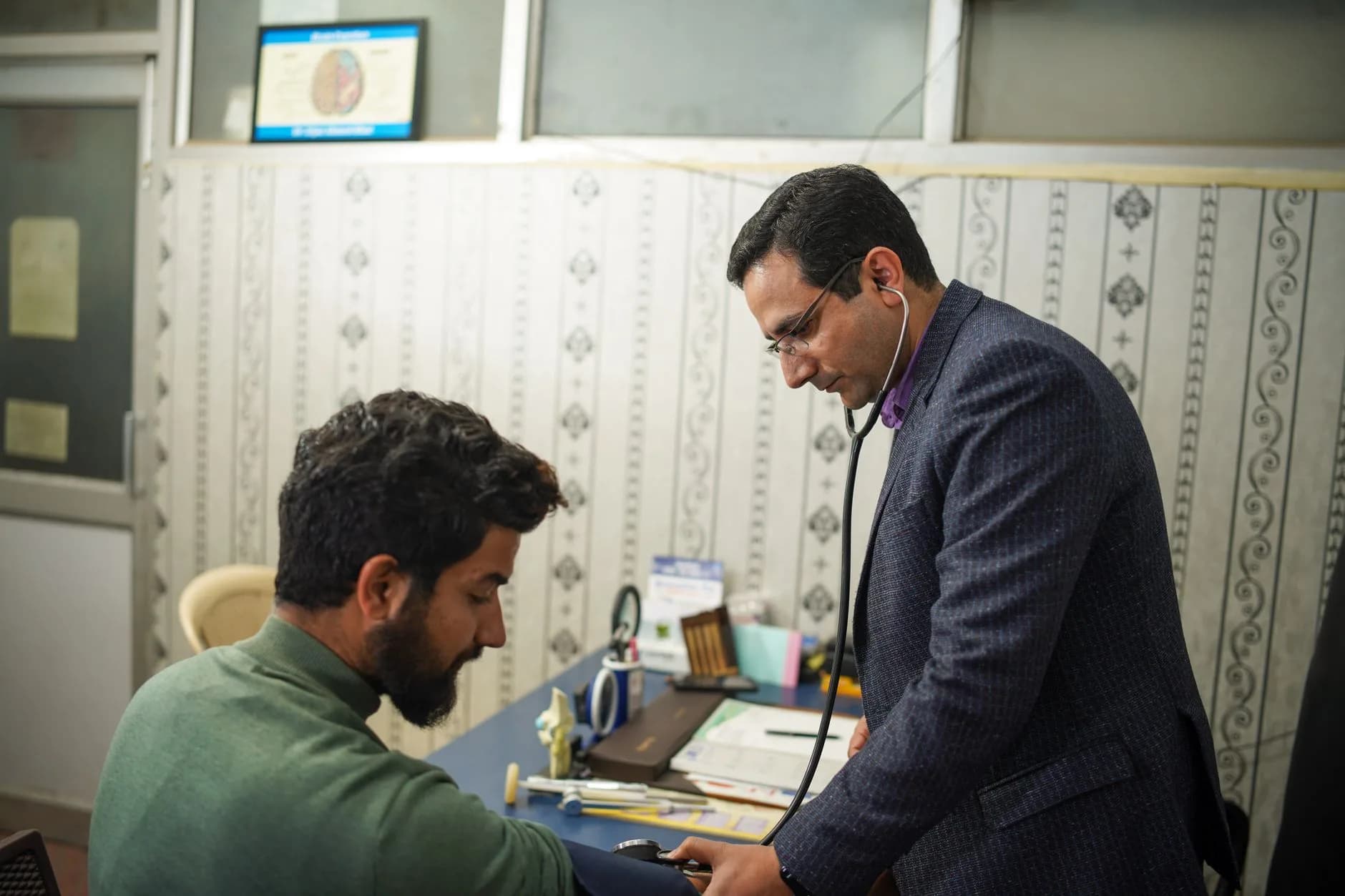 A doctor uses a stethoscope for a patient's health check-up in a clinic.