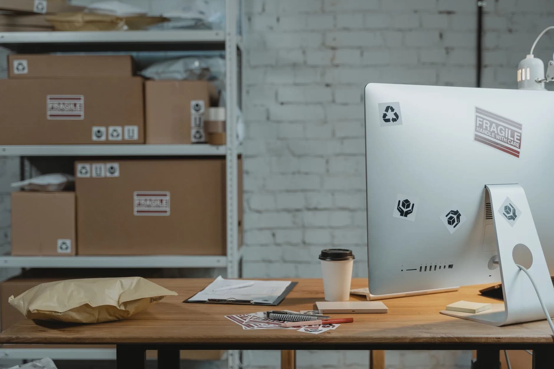 Contemporary office setup with a computer, coffee, and parcels on a wooden desk.